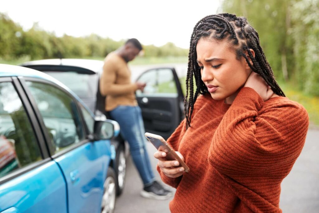 A woman who was in a car crash looks through her phone to call a personal injury lawyer to help her with her car accident case